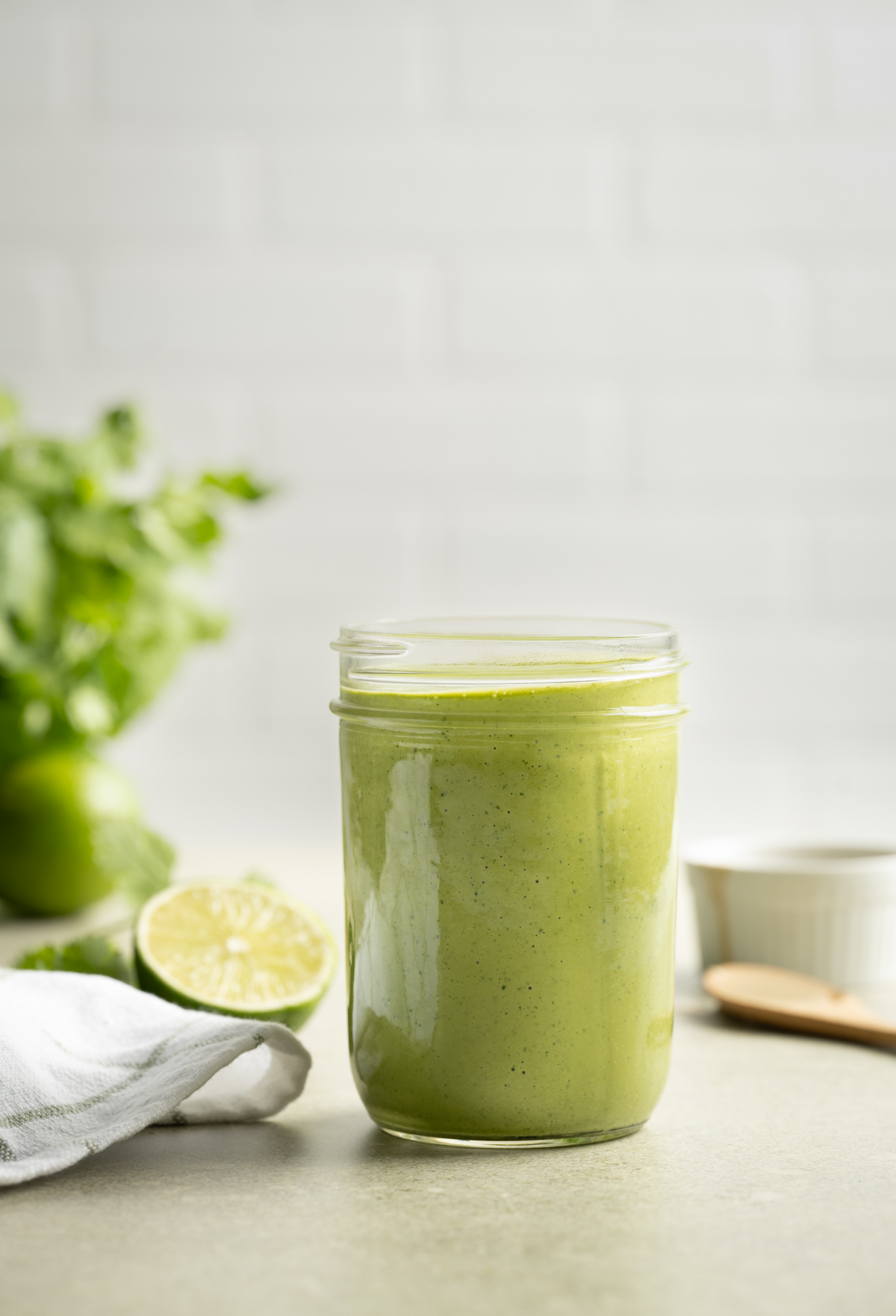 green lime tahini dressing in a mason jar half a lime jar of cilantro