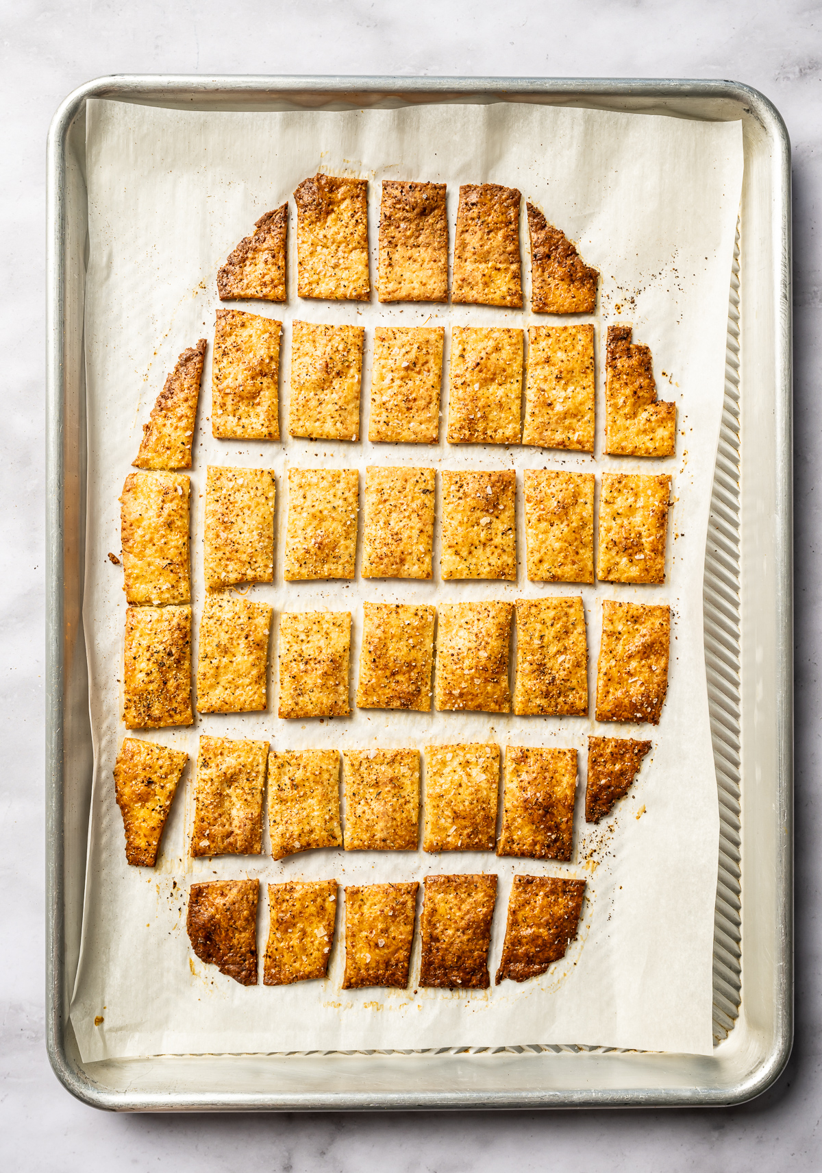 golden brown baked cheese crackers on tray with parchment paper