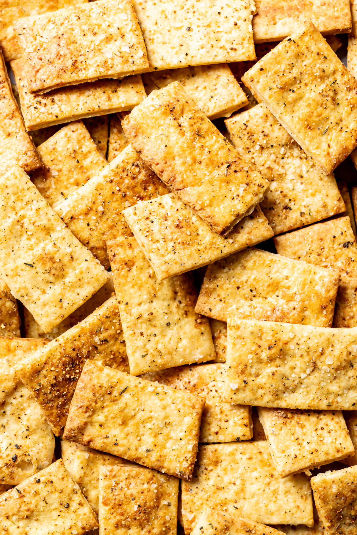 A pile of golden baked cheese crackers with lemon pepper seasoning