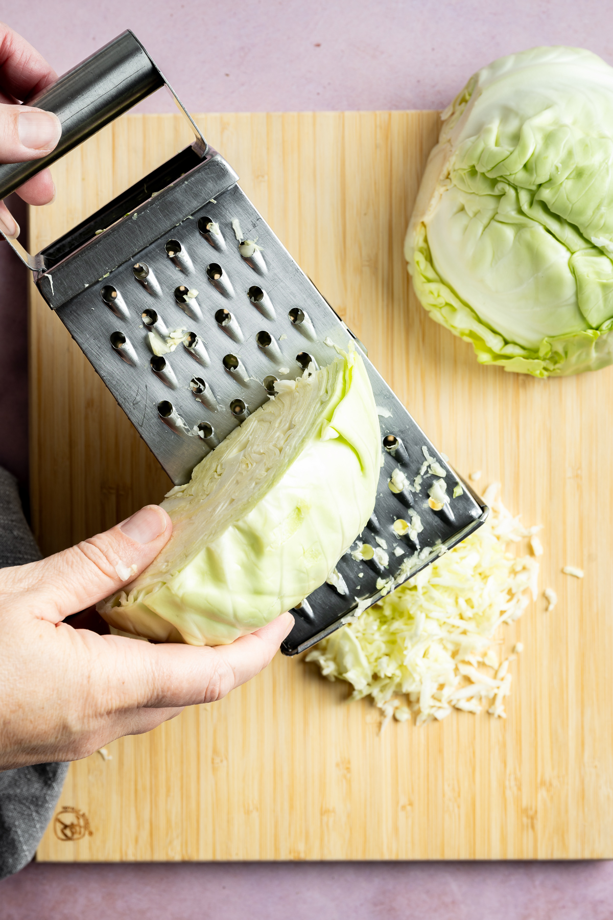 green cabbage being shredded with box grater