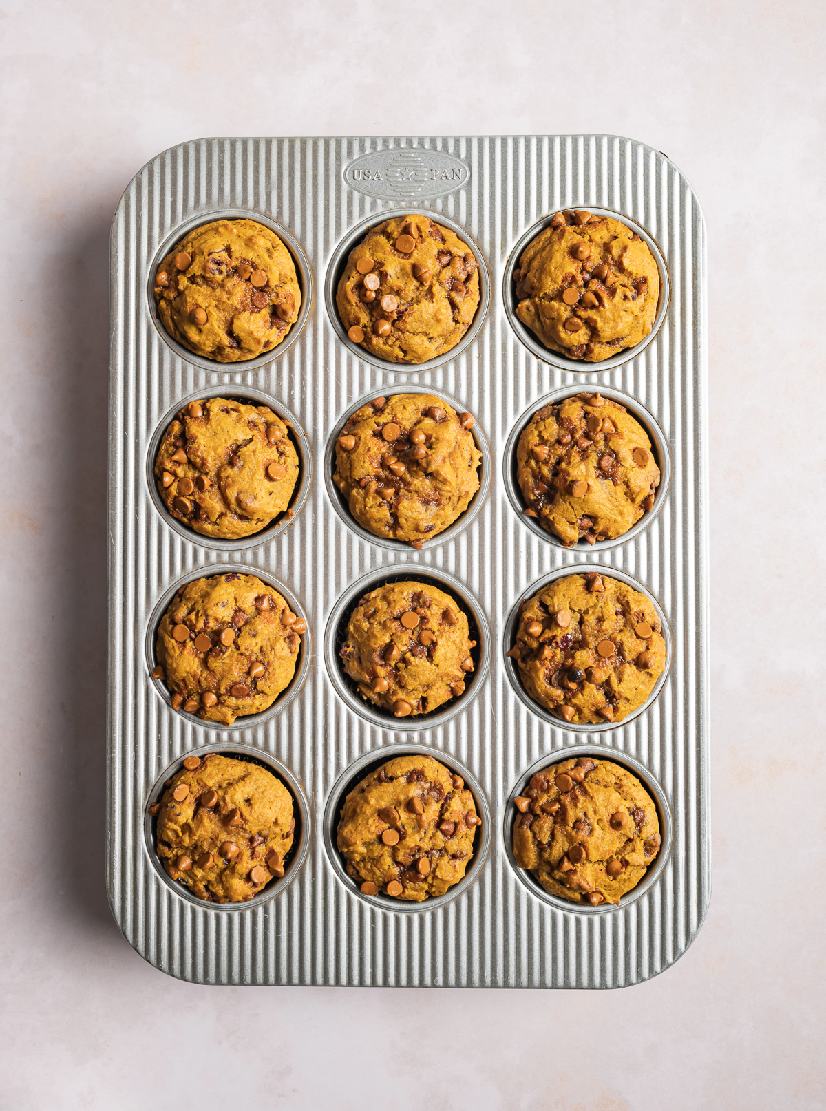 12 (twelve) baked cinnamon pumpkin muffins in a muffin tin
