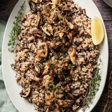 large platter with wild rice and sauteed mushrooms lemon wedge fresh thyme