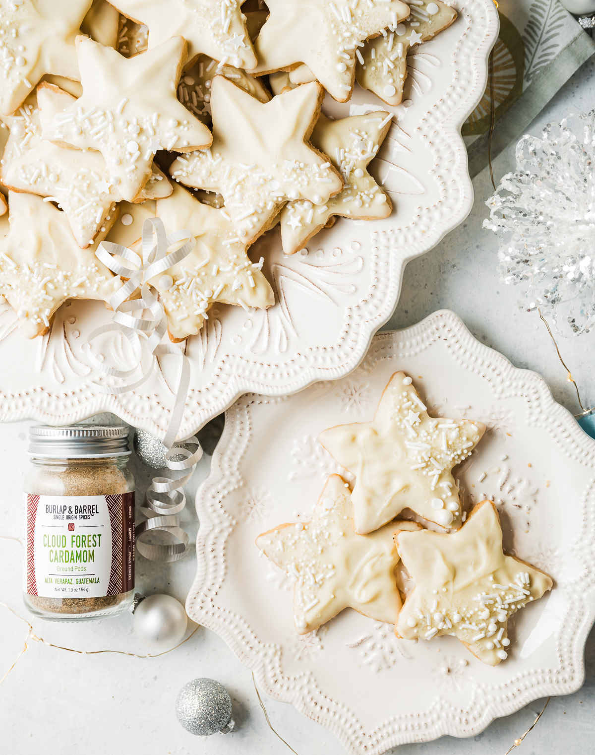 star shaped white chocolate dipped cardamom shortbread cookies on a white plate jar of cardamom
