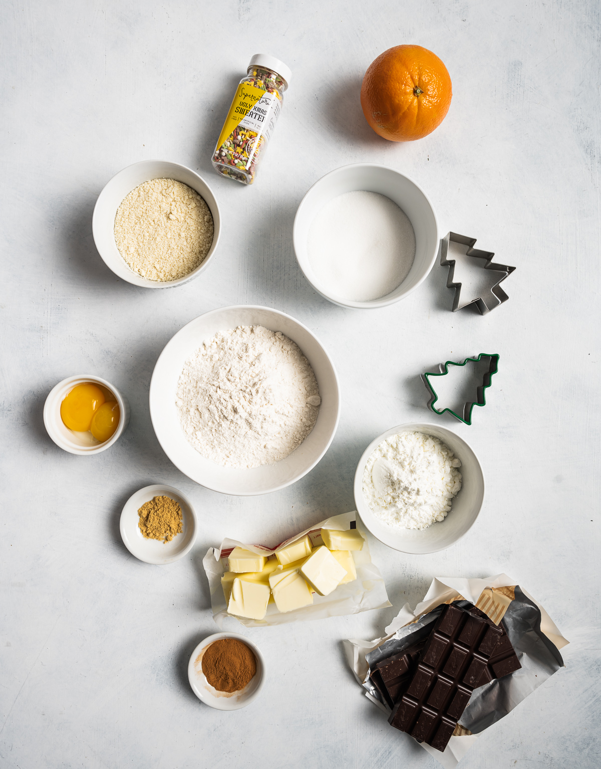 various bowls of ingredients for cookies flour butter sugar cornstarch an orange egg yolks container of sprinkles chocolate bar