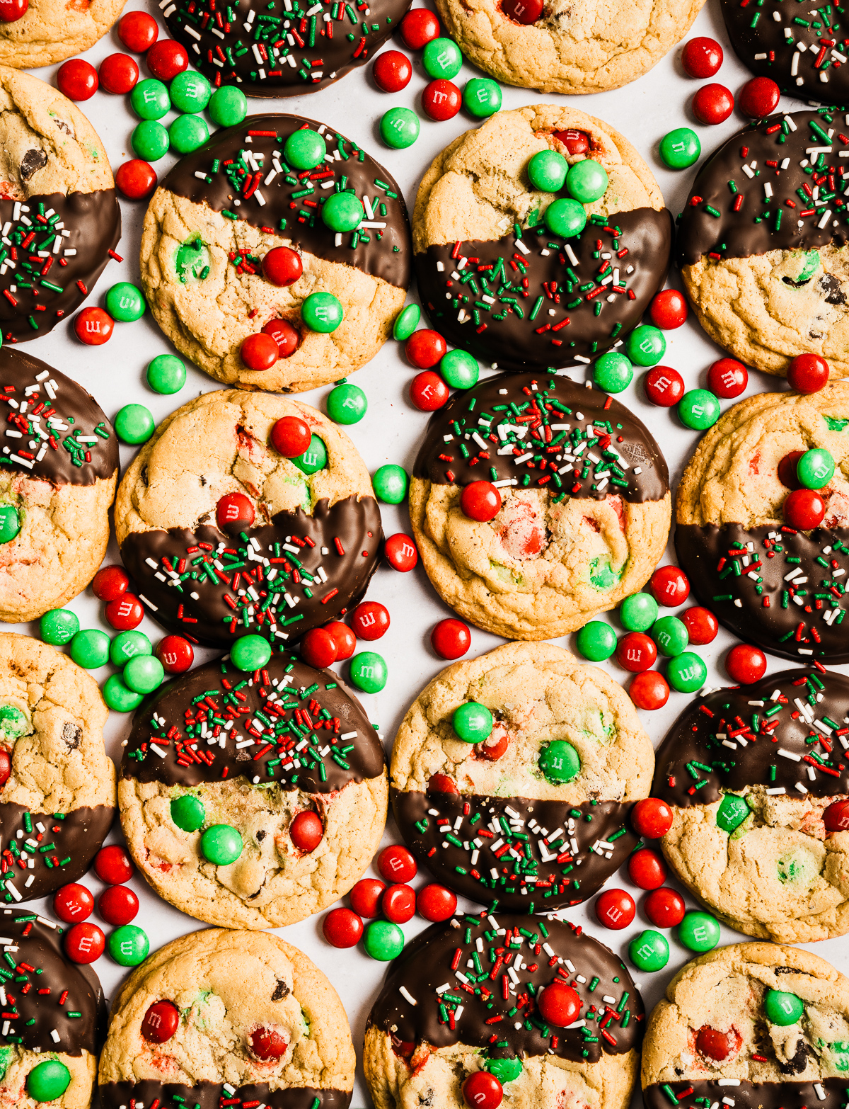 red and green M&M chewy chocolate chip cookies half dipped in chocolate decorated with red white and green sprinkles