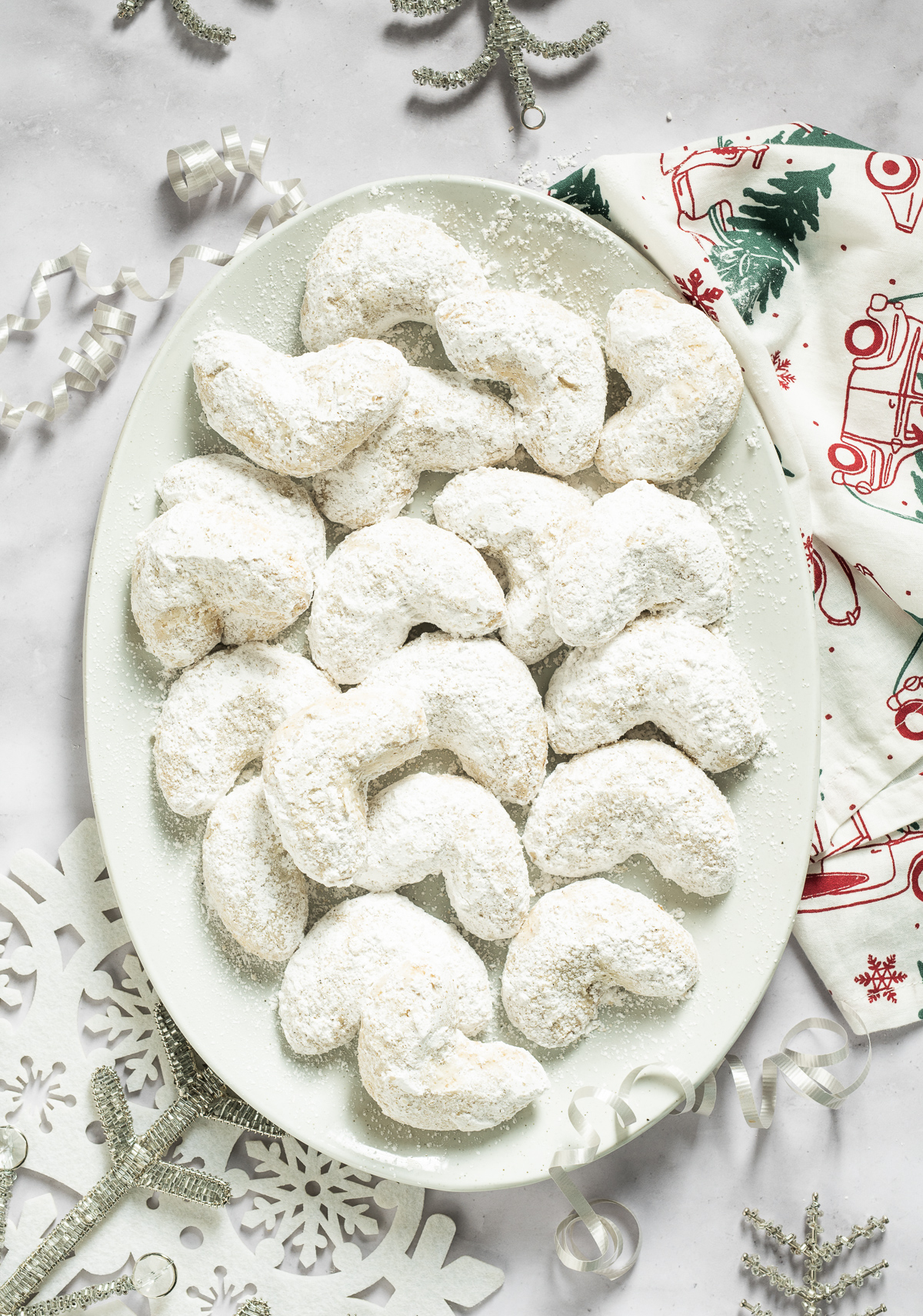 white almond crescent cookies on a white plate green and red christmas napkin white and silver snowflakes