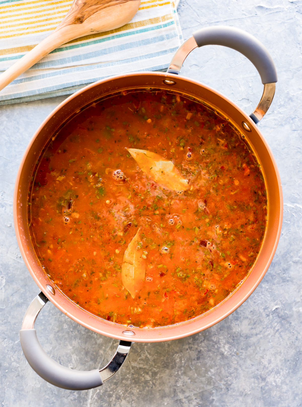 pot of jambalaya with broth and bay leaves cooking