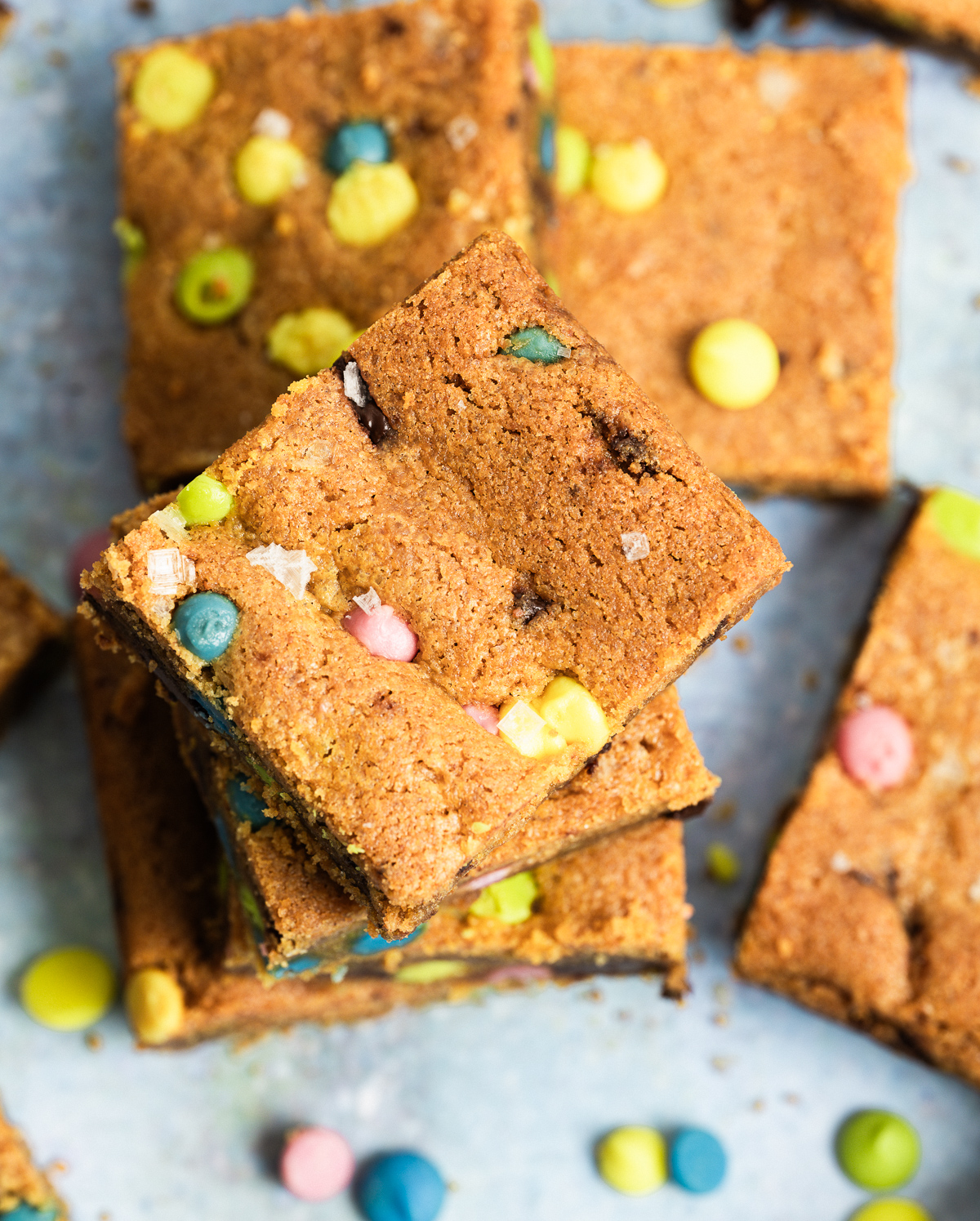 stack of chocolate chip cookie bars rainbow chips scattered about