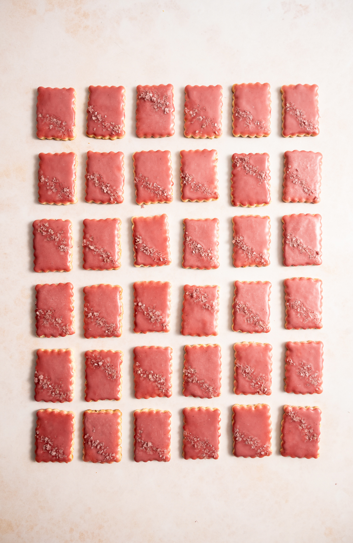 scalloped edge rectangular cookies with a pink glaze and pink flake salt lime macadmia butter cookies with hibiscus glaze