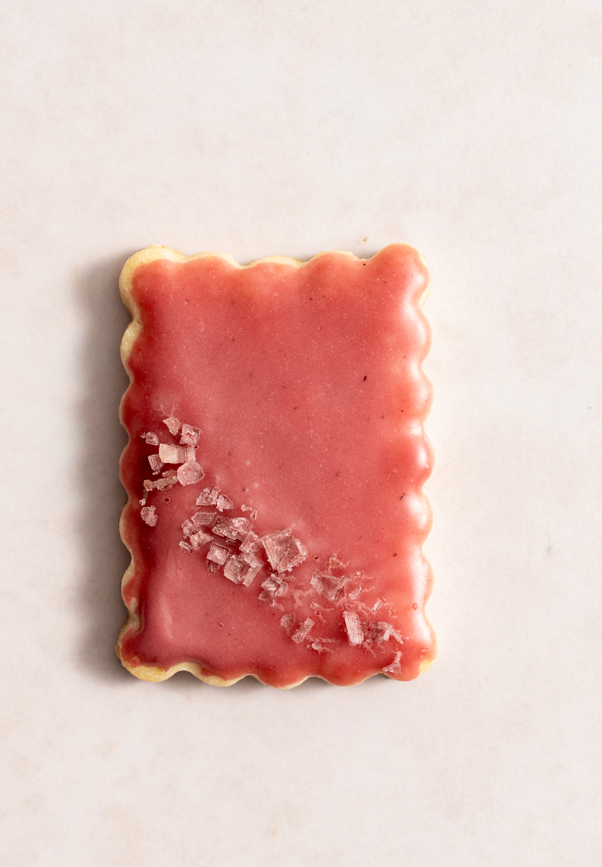 one scalloped edge rectangular cookies with a pink glaze and pink flake salt lime macadmia butter cookies with hibiscus glaze