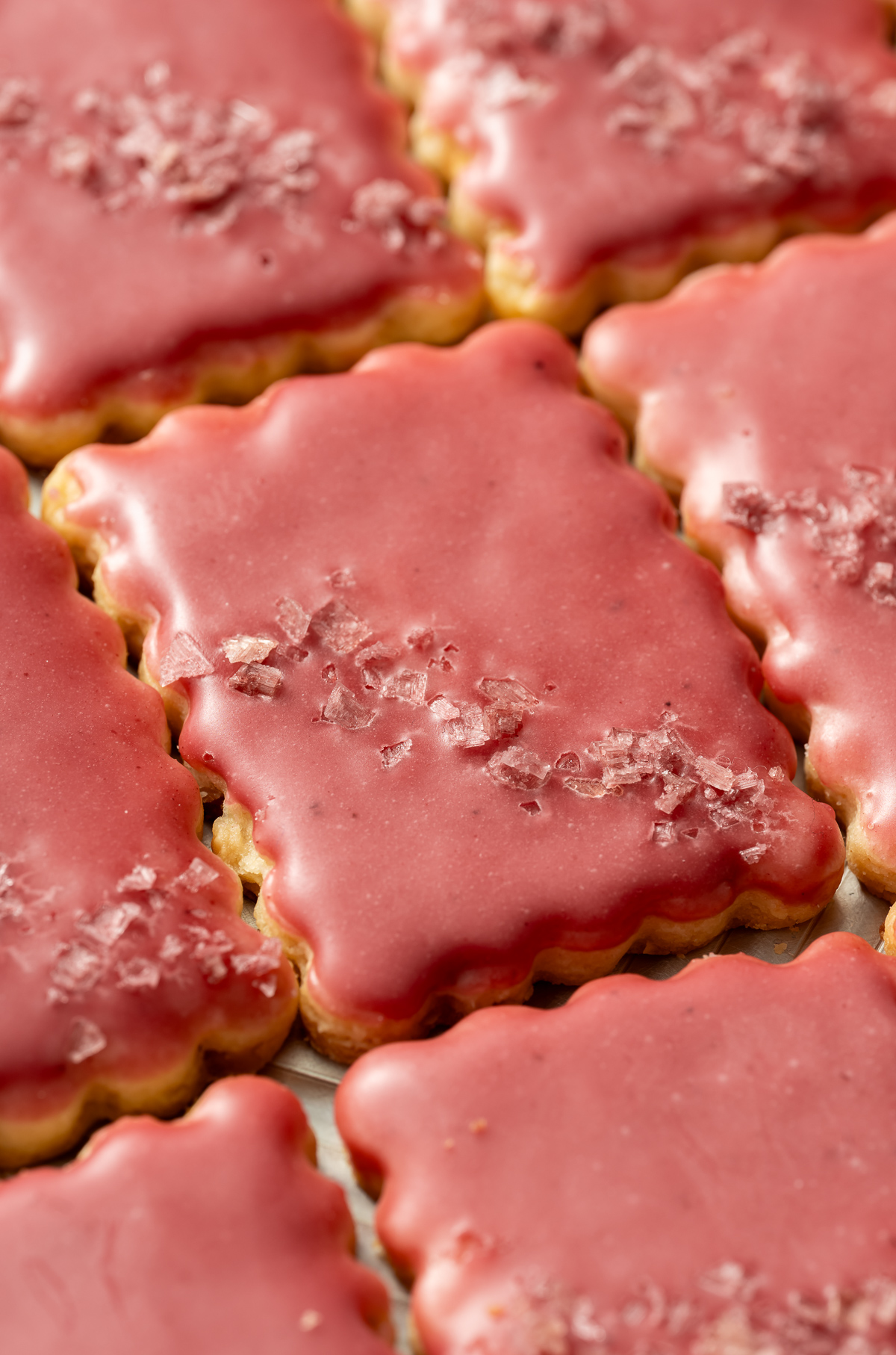 scalloped edge rectangular cookies with a pink glaze and pink flake salt lime macadmia butter cookies with hibiscus glaze