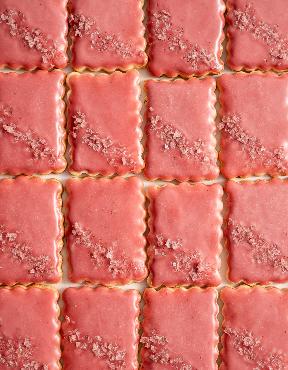 scalloped edge rectangular cookies with a pink glaze and pink flake salt lime macadmia butter cookies with hibiscus glaze