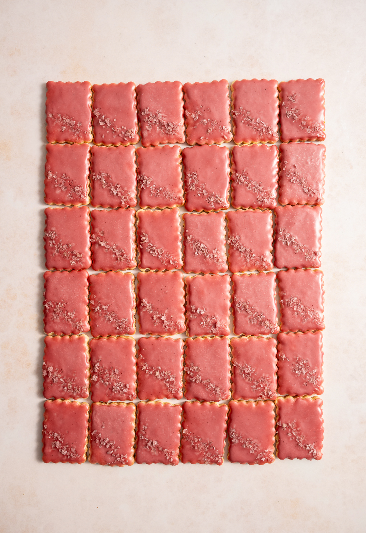 scalloped edge rectangular cookies with a pink glaze and pink flake salt lime macadmia butter cookies with hibiscus glaze