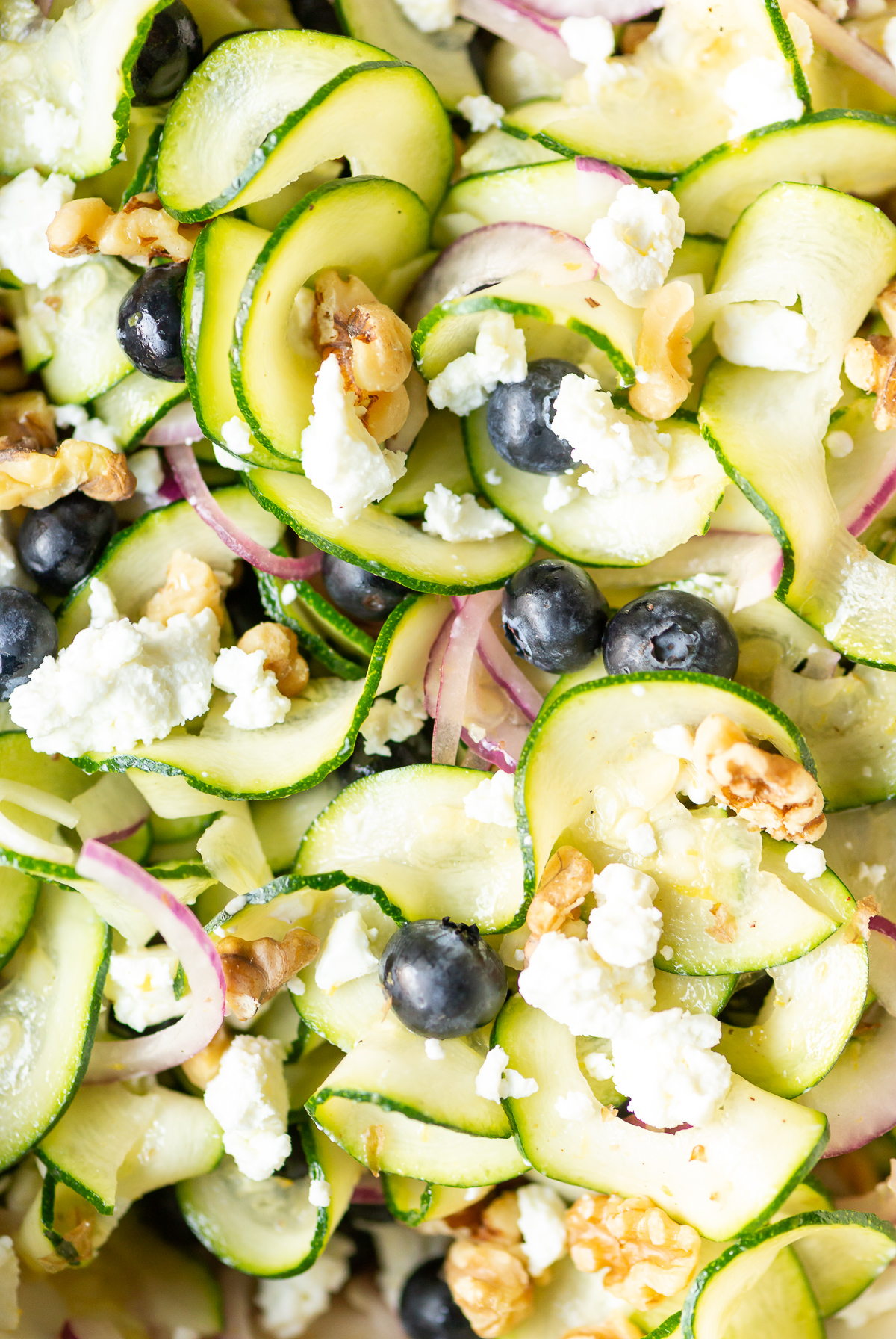 zucchini ribbon salad with red onion slices blueberries walnut pieces and goat cheese crumbles