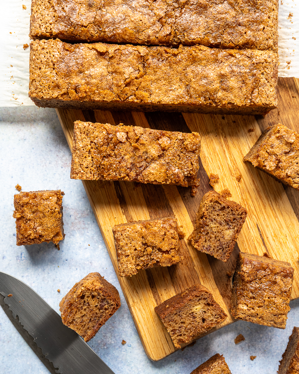 banana bread butter mochi cut into slices and squares on a wood cutting board