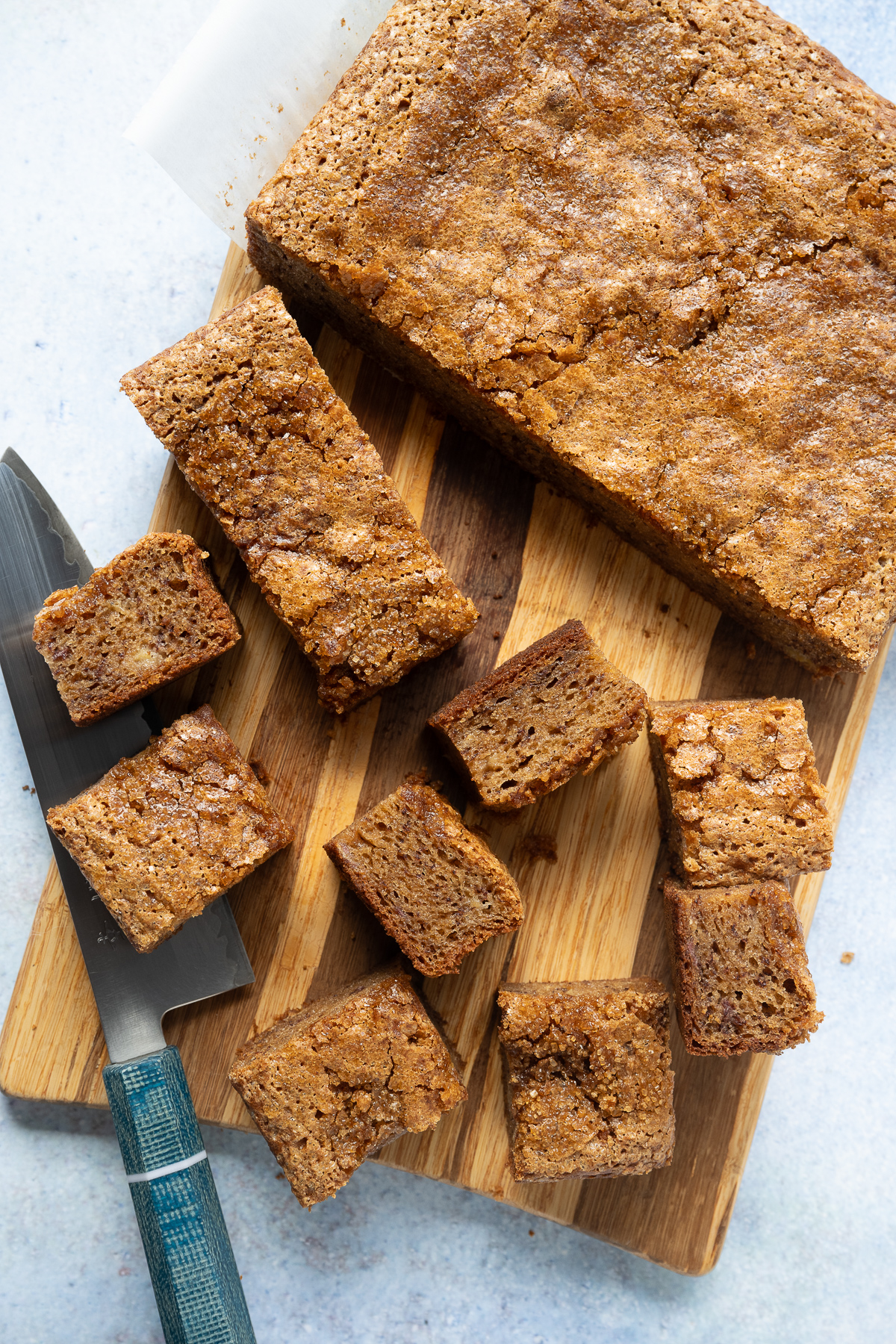 banana bread butter mochi cut into slices and squares on a wood cutting board