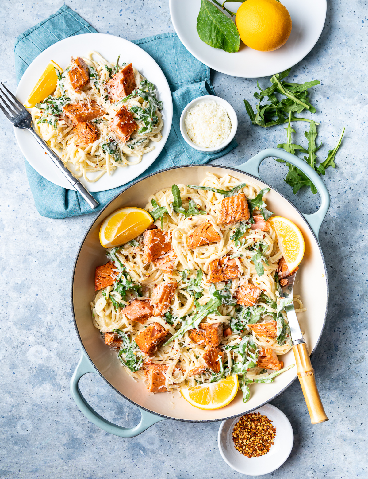 sockeye salmon pasta in bowls with lemon slices and arugula small bowl of parmesan cheese fork plate with whole meyer lemon 